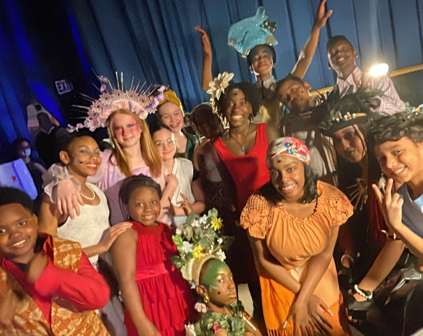 A group of students dressed in "Once on This Island" costumes smile and pose for a picture.